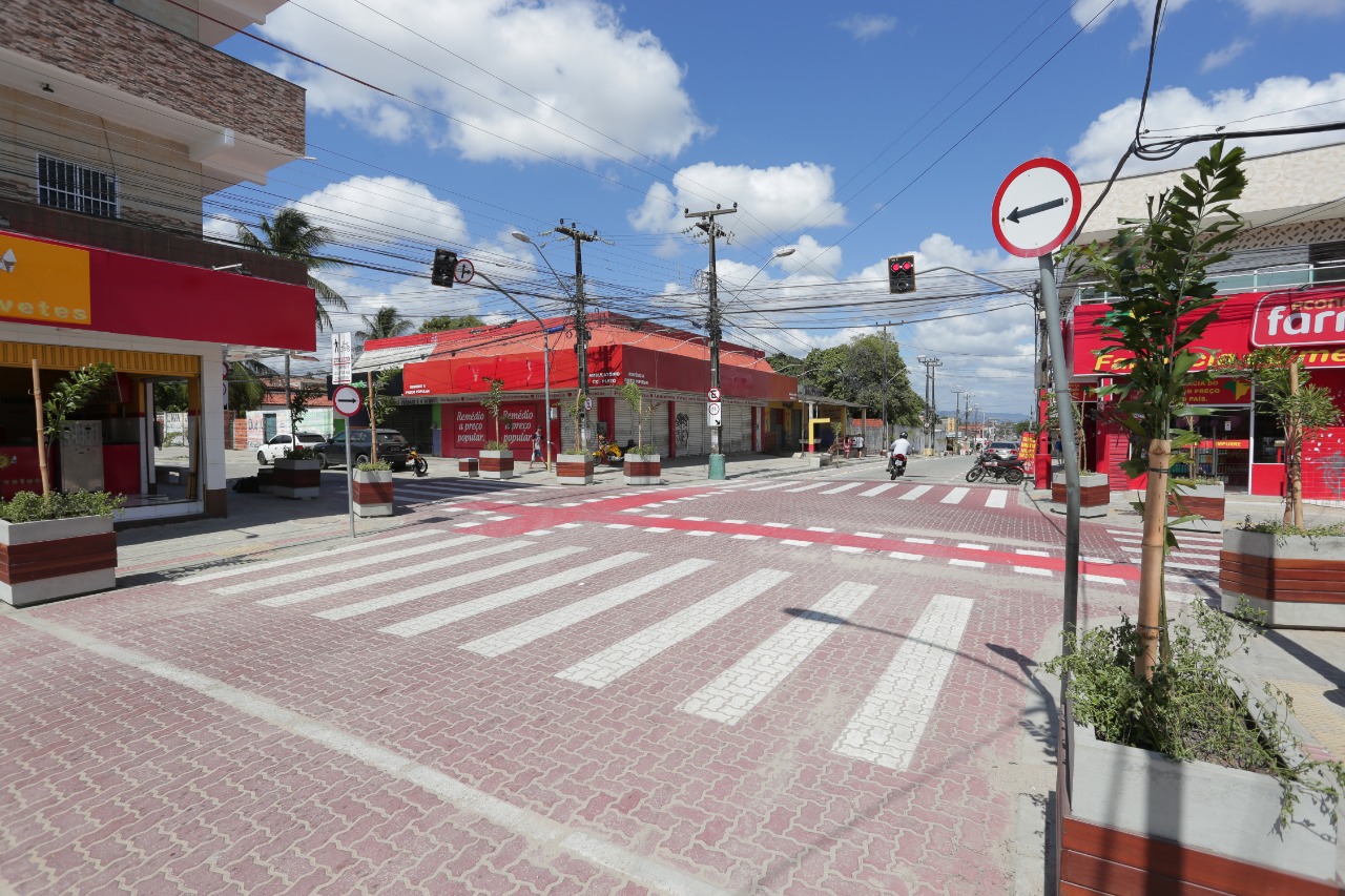 rua com piso intertravado, faixa de pedestre e comércios ao redor